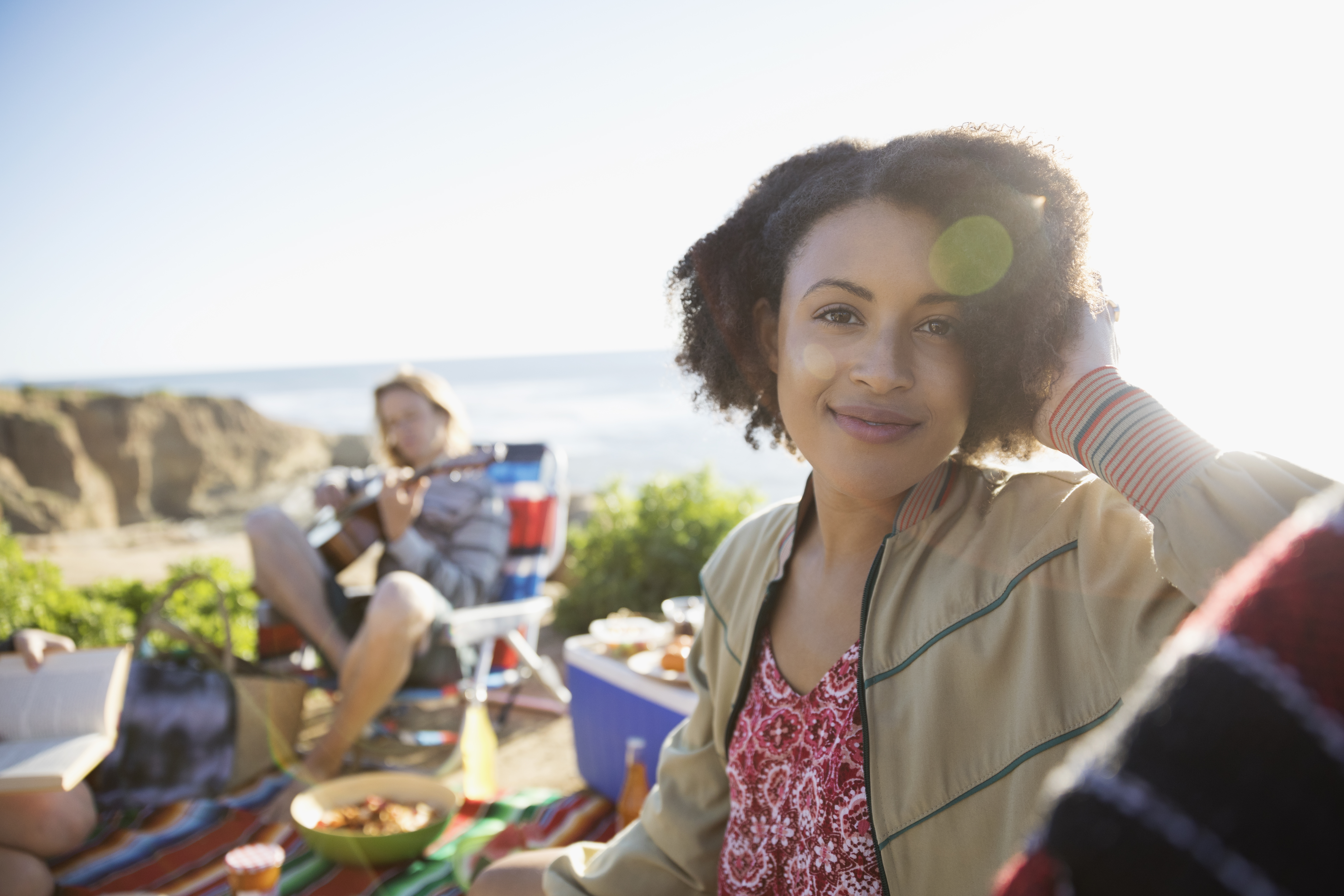 Portrait smiling young woman enjoying picnic with friends on sunny beach