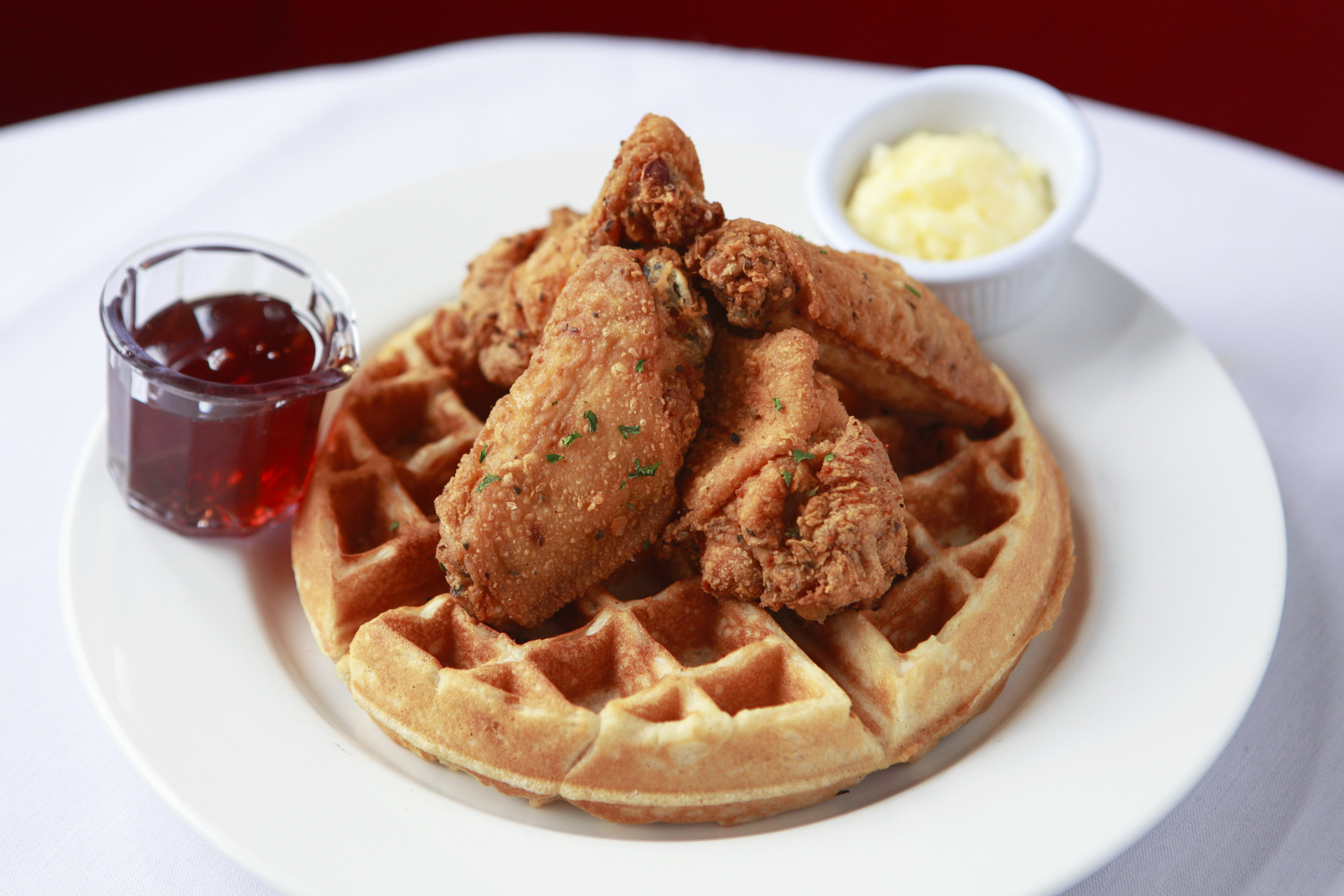 fried chicken and waffles on restaurant table with syrup and butter