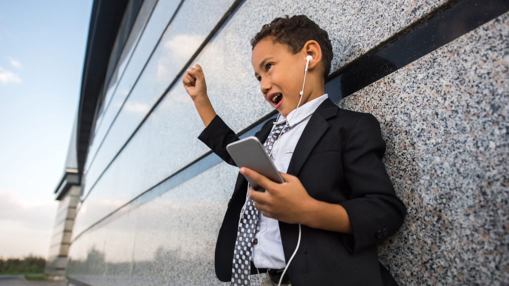 Small African American business boy singing while listening MP3 player.